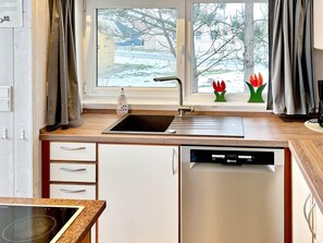 A kitchen with a window, a sink, a dishwasher, and a stove. - Holiday Home in Otterndorf (Otterndorf)