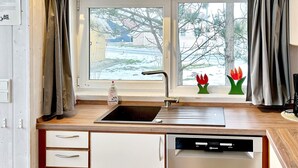 Una cucina con finestra, lavello, lavastoviglie e fornelli.