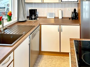 A modern kitchen with a dishwasher, a coffee maker, and a stove. - Holiday Home in Otterndorf (Otterndorf)