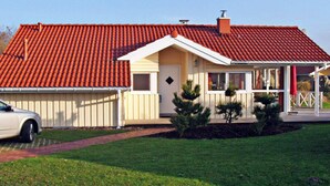 Una casa a un piano con tetto in tegole rosse, un portico e un piccolo giardino antistante.