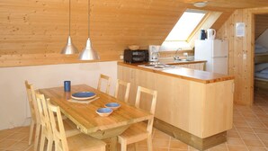 A wooden interior with a kitchen and dining area, featuring a wooden table, chairs, a small island with a sink, and pendant lights. - 6 Person Holiday Home in Ringkobing-by Traum (Ringkobing)