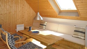 A cozy room with a wooden sloped ceiling, a skylight, a wooden dining table, a sofa, and patterned cushions. - 6 Person Holiday Home in Ringkobing-by Traum (Ringkobing)