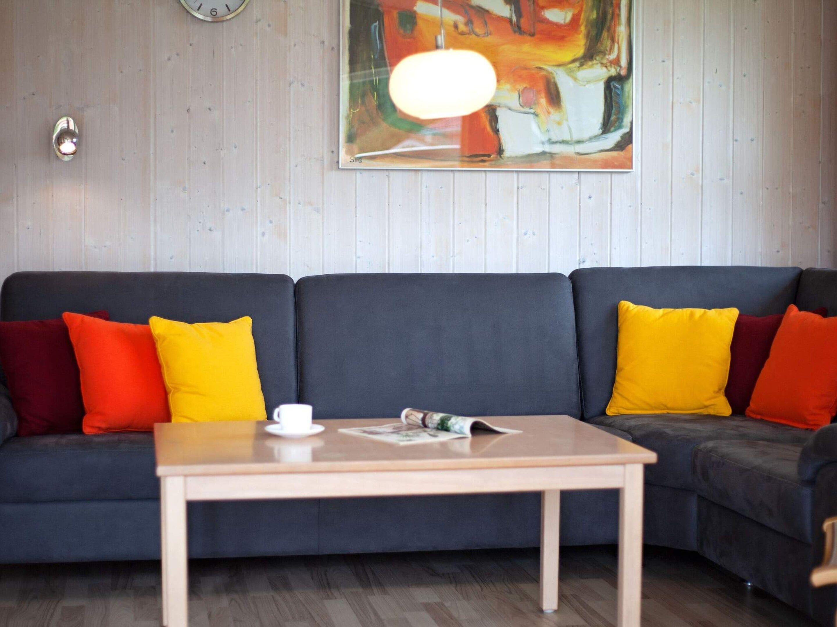 A modern living room with a dark-colored sofa, a wooden coffee table, and a colorful abstract painting on the wall.