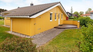 A yellow single-story house with a sloped roof, a small porch, and a gravel driveway. - Holiday Home in GrÃ¶mmitz (Groemitz)