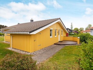 A yellow single-story house with a sloped roof, a small porch, and a gravel driveway. - Holiday Home in GrÃ¶mmitz (Groemitz)