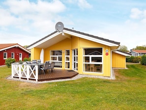 A yellow house with a deck, a satellite dish, and a number 45 sign. - Holiday Home in GrÃ¶mmitz (Groemitz)
