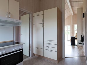 A kitchen with a stove, cabinets, and a view to the living area.