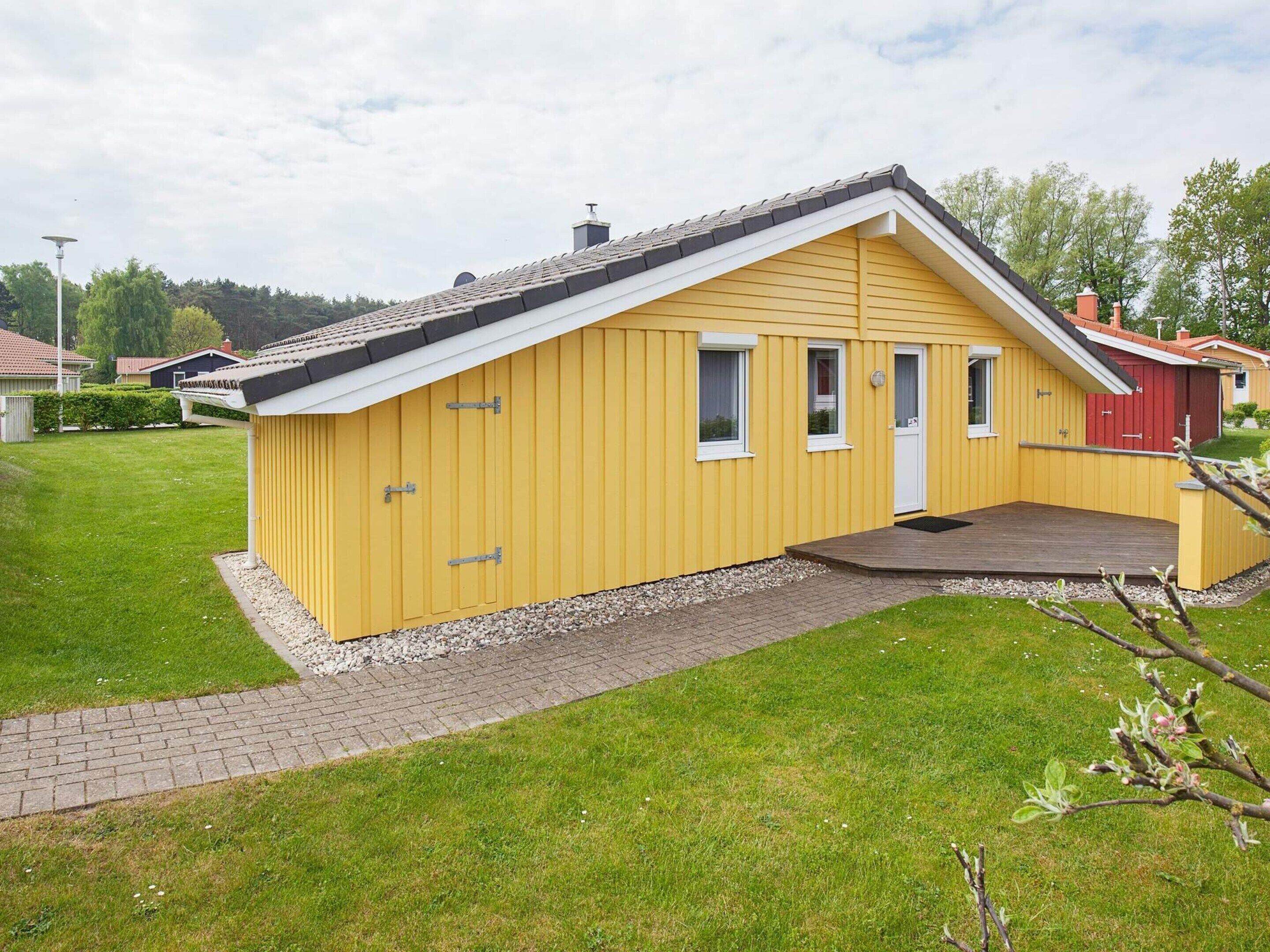 A yellow building with a sloped roof, a front porch, and a small garden area.