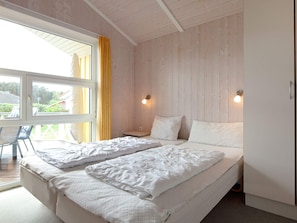 A bedroom with two beds, a window with curtains, and a view of the outdoors. - Holiday Home in GrÃ¶mmitz (Groemitz)