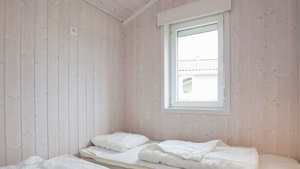 A room with two beds, a window, and wooden walls. - Holiday Home in GrÃ¶mmitz (Groemitz)