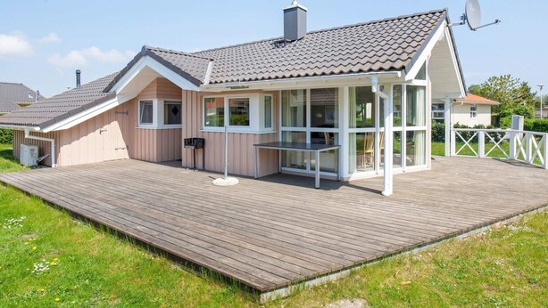 A modern house with a covered patio, a satellite dish, and a wooden deck.