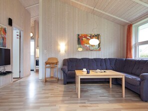 A modern living room with a wooden floor, a dark blue sofa, a wooden coffee table, and a painting on the wall. - Holiday Home in GrÃ¶mmitz (Groemitz)