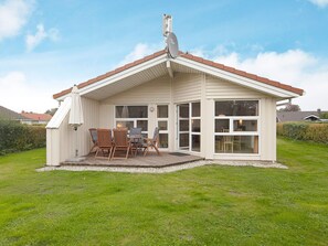 A single-story house with a covered patio, a satellite dish, and a small outdoor seating area with chairs and a table. - Holiday Home in Grömmitz (Groemitz)