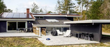 A modern house with a patio area, a covered outdoor seating area, and a garage.