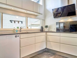 A modern kitchen with a dishwasher, a coffee maker, and a large window. - 4 Star Holiday Home in Nexo (Nexø)