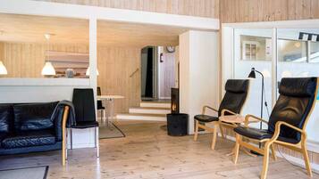 Un interior moderno con techo de madera, un sofá de cuero negro y dos sillones de cuero.