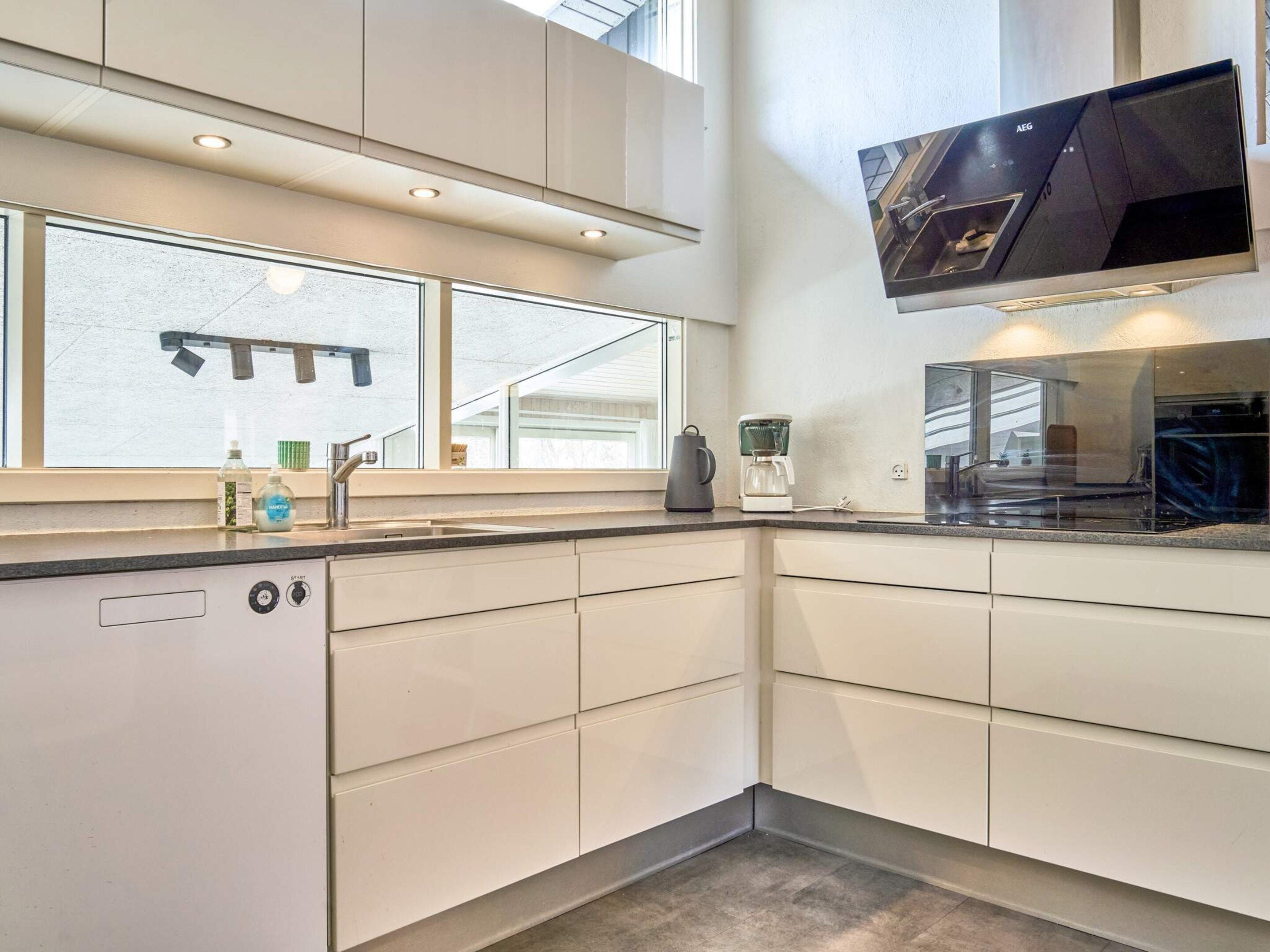 A modern kitchen with a dishwasher, a coffee maker, and a large window.