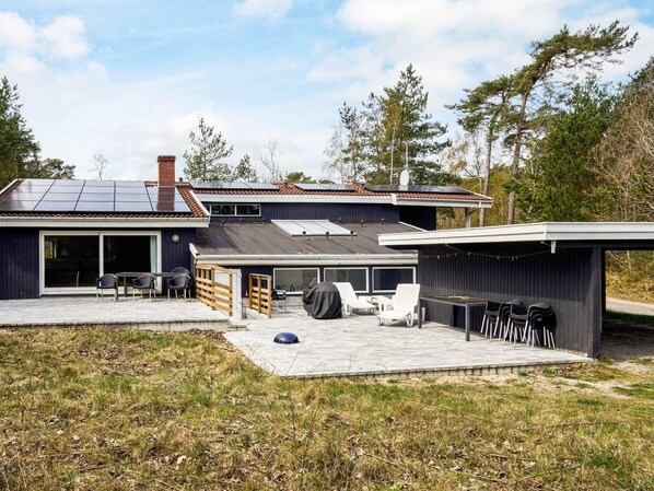 Une maison moderne dotée d’un patio, d’un espace extérieur couvert aménagé en salon et d’un garage.