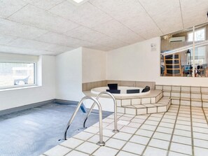 Un espace bien-être comprenant un jacuzzi, un escalier et une fenêtre.