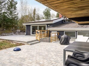 Une maison moderne dotée d’un patio, d’une terrasse couverte et d’une grande fenêtre.
