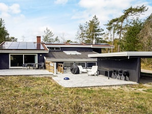 Une maison moderne dotée d’un patio, d’un espace salon extérieur et d’une partie abritée.