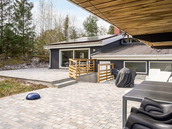 A modern house with a patio area, a covered deck, and a large window.
