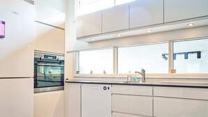 A modern kitchen with white cabinetry, a built-in oven, and a window above the sink.