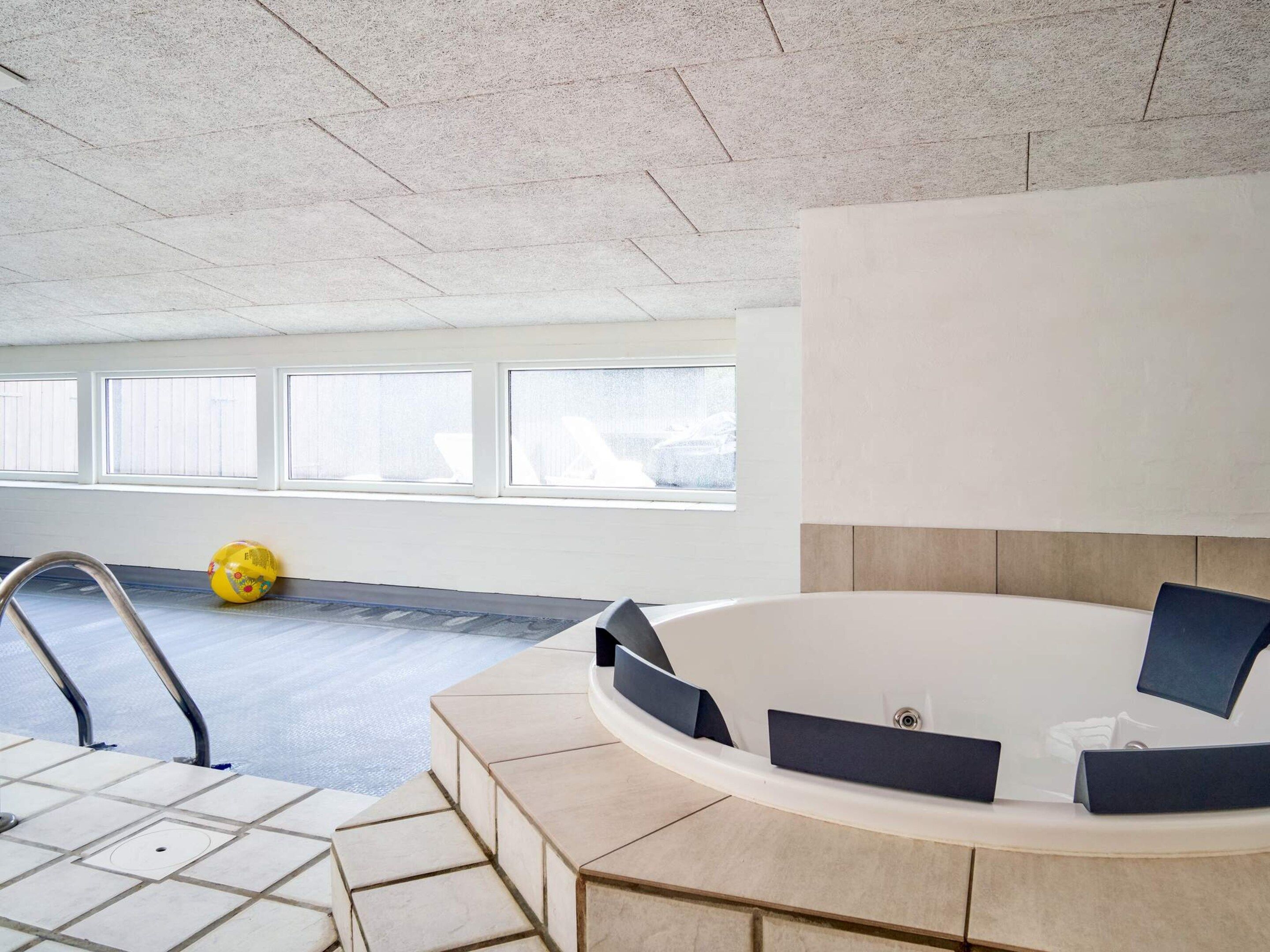 Ein modernes Badezimmer mit Badewanne, Duschbereich und einem Fenster mit Jalousien.