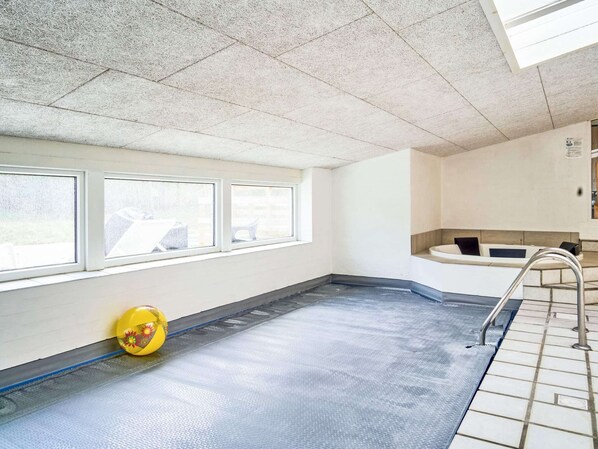 A swimming pool with a blue floor, a yellow exercise ball, and a white bench. - 4 Star Holiday Home in Nexo (Nexø)