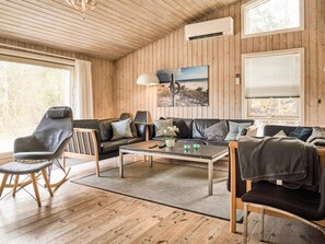 A cozy living room with wooden walls, a sofa, a coffee table, and a chair.
