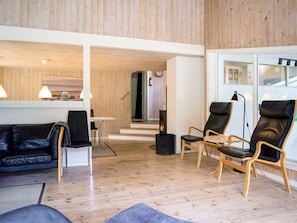 Un intérieur moderne avec un plafond en bois, un canapé en cuir noir et deux fauteuils en cuir.