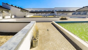 A courtyard with a swimming pool, a grassy area, and a building with multiple windows and a flat roof. - 6 Person Holiday Home in Brovst-by Traum (Brovst)