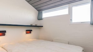 A bedroom with a bed, a window, a shelf with decorative items, and wall-mounted lights. - 6 Person Holiday Home in Brovst-by Traum (Brovst)