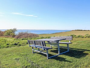 A picnic table and bench in a grassy field with a view of the sea. - Spacious Holiday Home in TranekÃ¦r near Sea (Tranekaer)