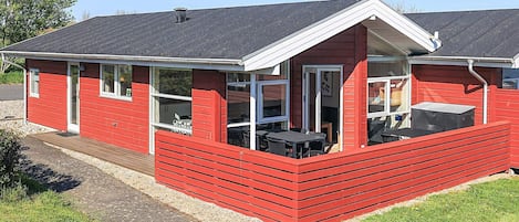 Una casa de madera roja con un porche, una ventana y una puerta.