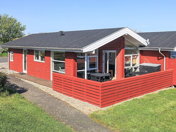 Una casa de madera roja con un porche, una ventana y una puerta.