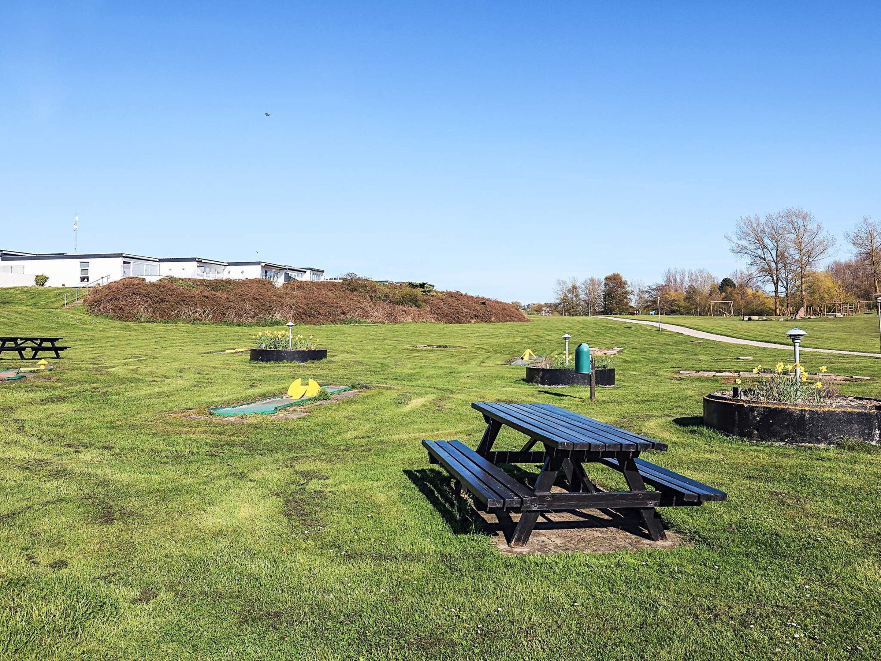 A picnic area with benches, a small garden, and a pathway leading to a building.