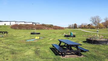 A picnic area with benches, a small garden, and a pathway leading to a building.