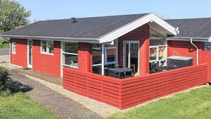 A red single-story building with a covered patio area and a small outdoor seating space. - Spacious Holiday Home in TranekÃ¦r near Sea (Tranekaer)