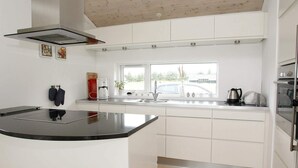 A modern kitchen with white cabinetry, a black countertop, and a built-in oven.