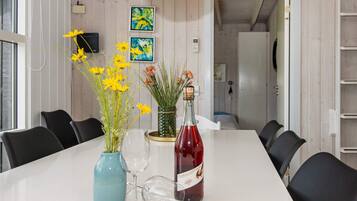 A dining table with chairs, a bottle of red wine, and vases with flowers.