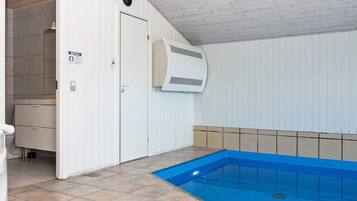 En swimmingpool med blå interiør, en hvid dør og et flisebelagt gulv.