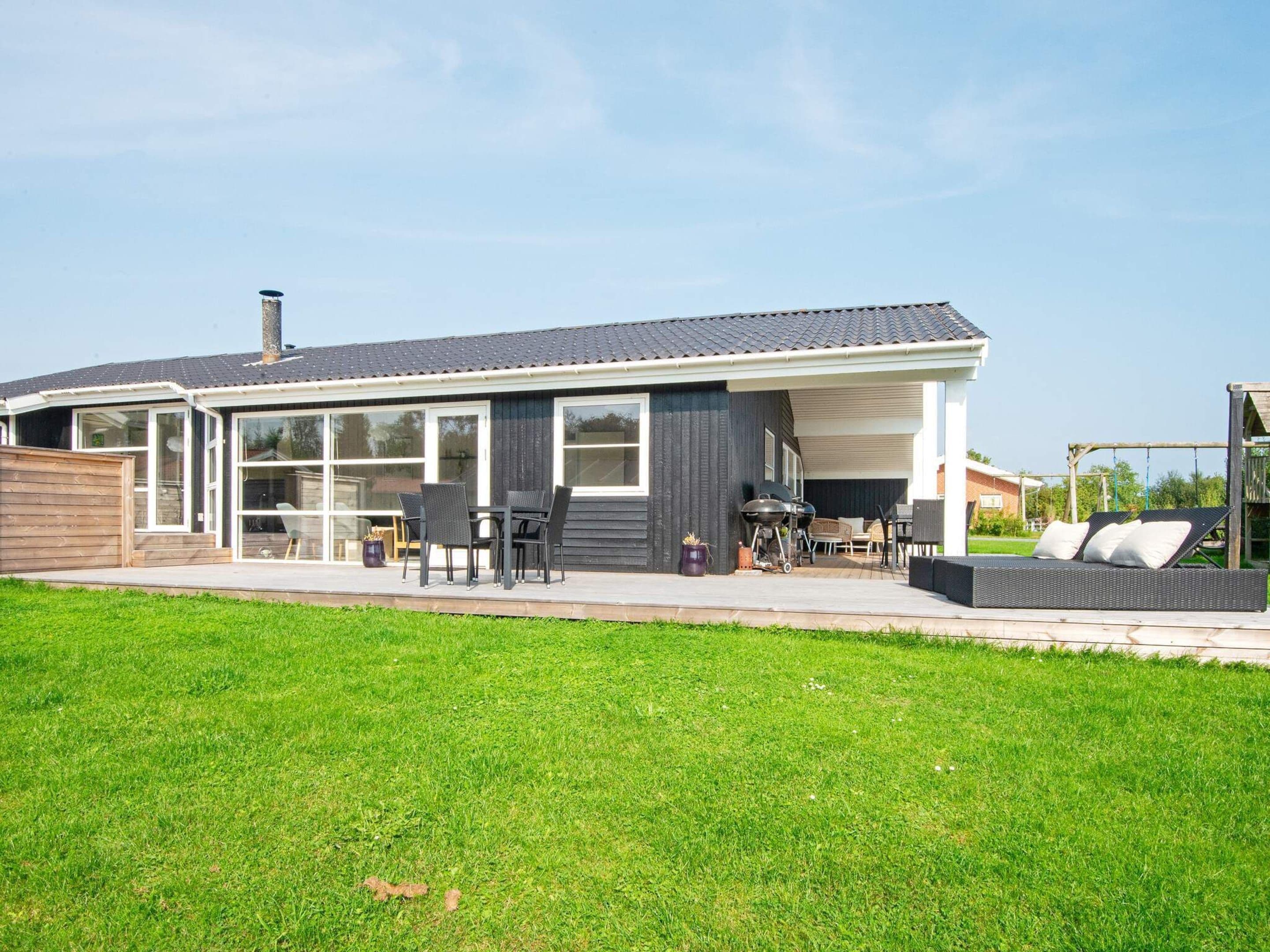 A modern house with a covered patio, a barbecue area, and a swing set.