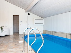 An indoor swimming pool with a tiled floor, a white wall with a door, and a white ceiling. - 4 Star Holiday Home in Juelsminde (Horsens)