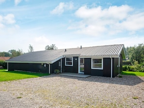 A two-story house with a sloped roof, a covered porch, and a gravel driveway. - 4 Star Holiday Home in Juelsminde (Horsens)