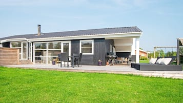A modern house with a covered patio, outdoor seating, and a barbecue area.