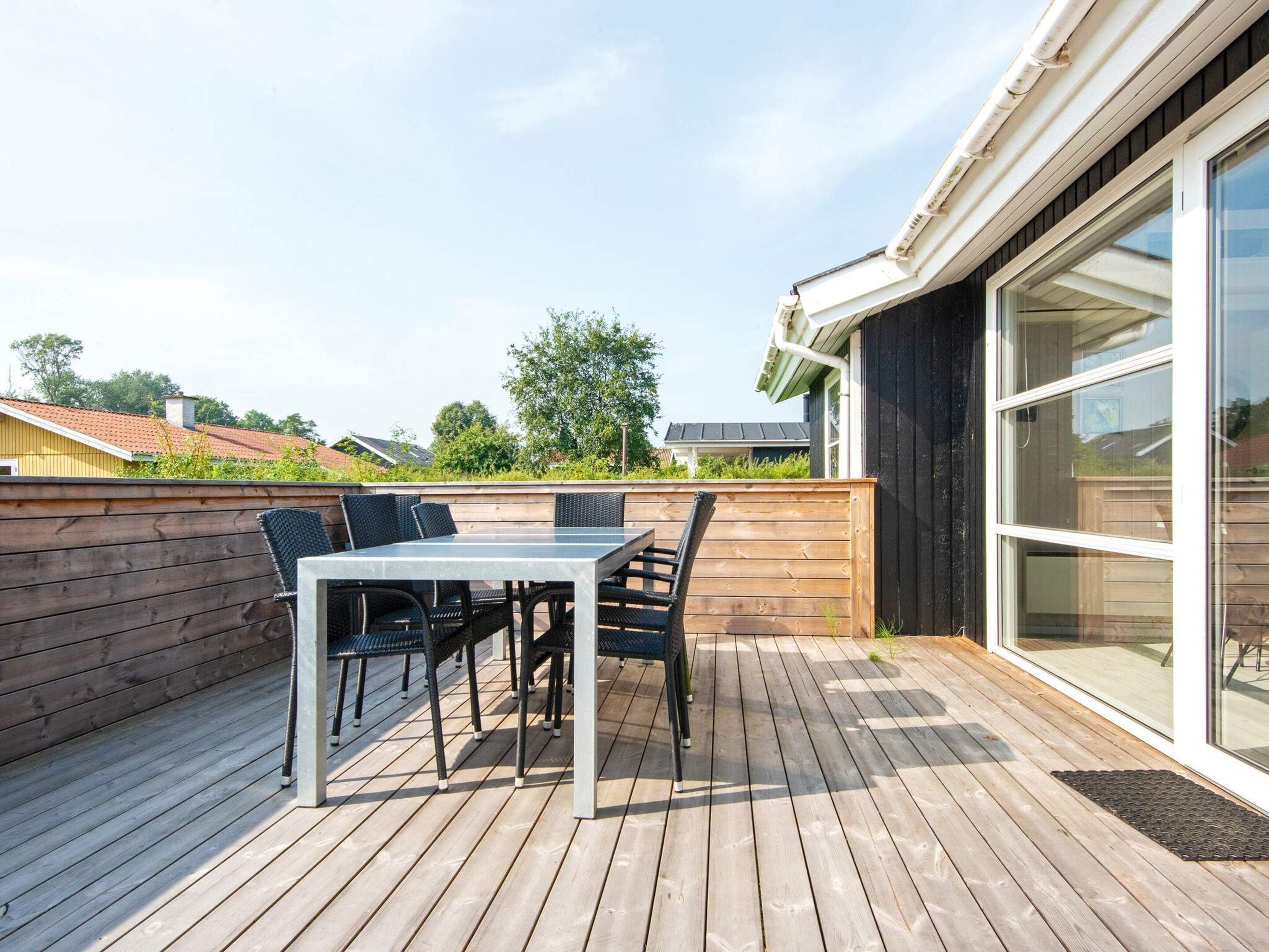 A wooden deck with a table and chairs, a glass door, and a view of the neighborhood.