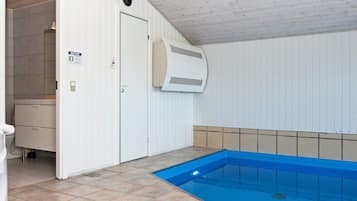 A swimming pool with a blue interior, a white door, and a tiled floor.