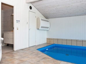Een zwembad met een blauw interieur, een witte deur en een betegelde vloer.