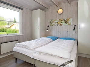 Une chambre à coucher comprenant un lit, une armoire, une fenêtre et un luminaire fixé au mur.